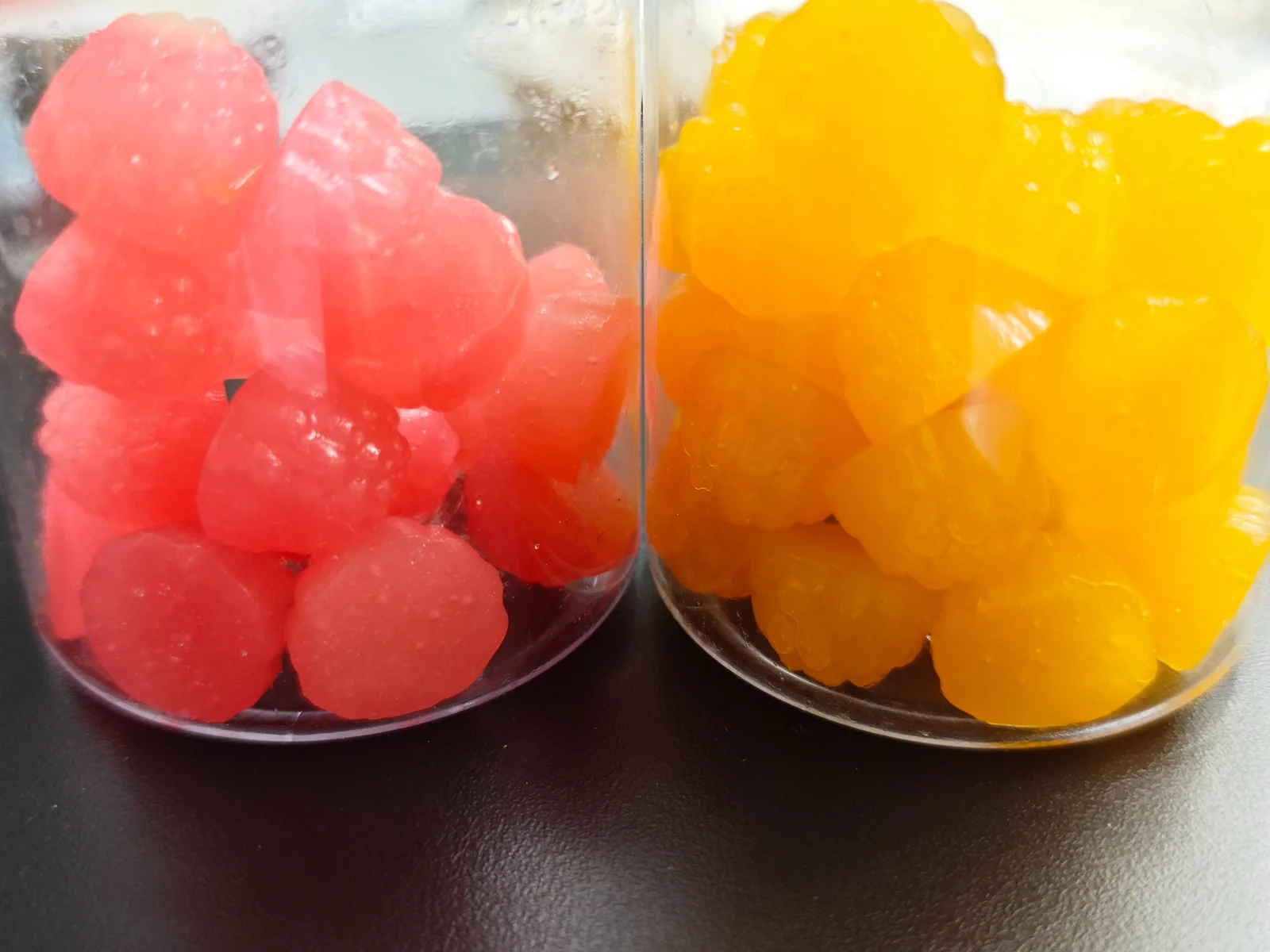 Pink and yellow gummy samples displayed in two clear containers, accompanying the comparison of taste and texture considerations for magnesium glycinate gummies and capsules.