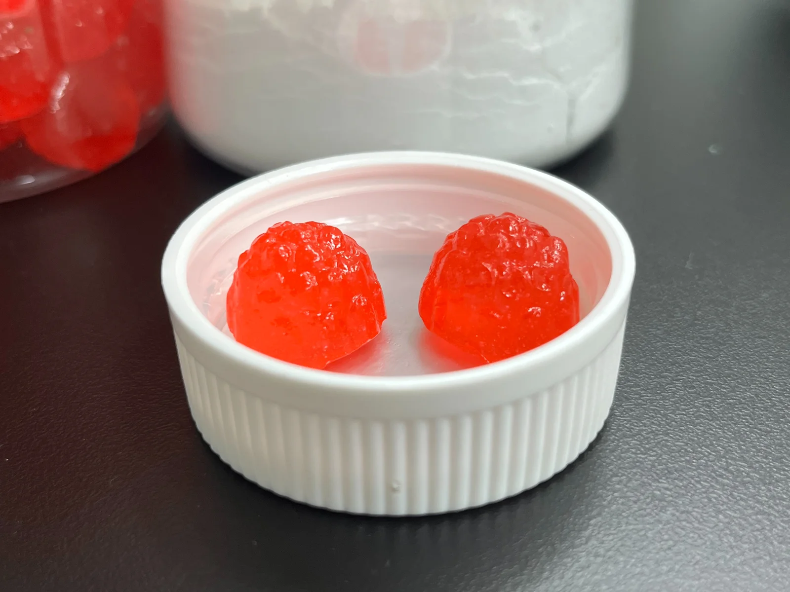 Two red berry-shaped gummy samples in a white bottle cap, introducing magnesium glycinate gummies and the product development directions discussed for supplement brands.