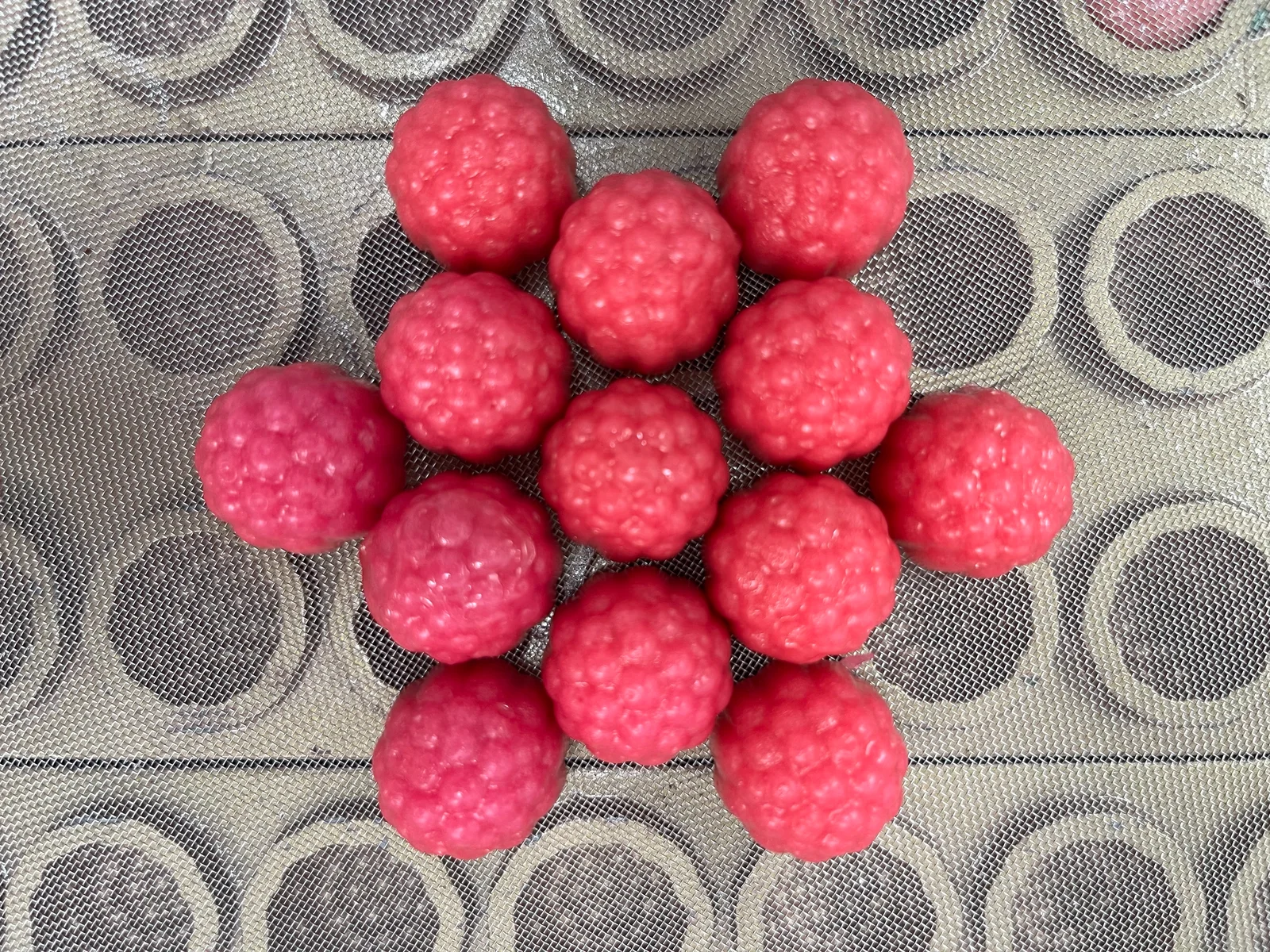Pink berry-shaped gummy samples grouped on a mesh surface, illustrating the article's discussion of magnesium glycinate gummy concepts for sleep support product development.