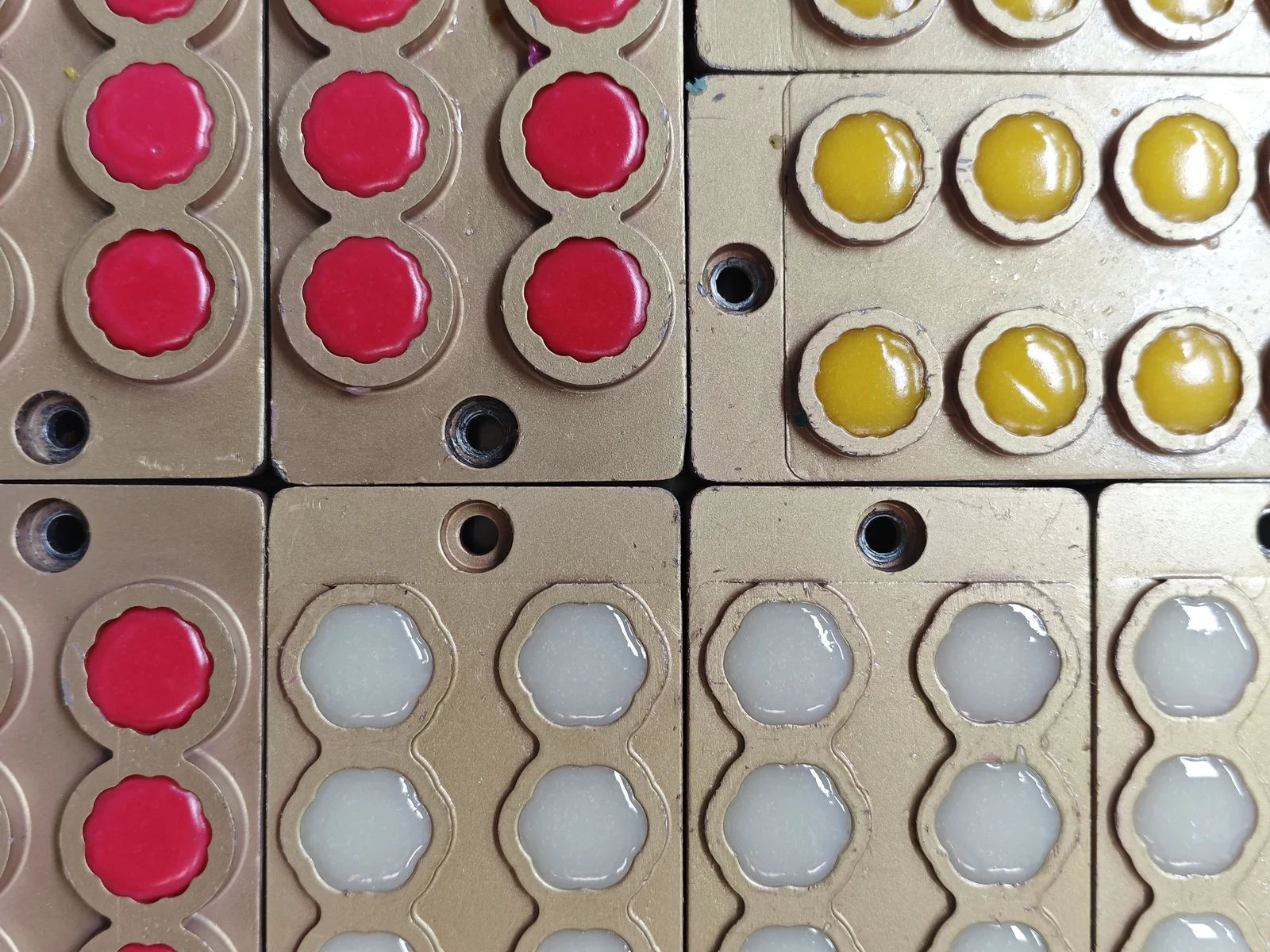 Pink, yellow and pale gummy mixtures in molds during formulation trials, illustrating probiotic strain selection alongside CFU per serving, ingredient compatibility and shelf-life targets.
