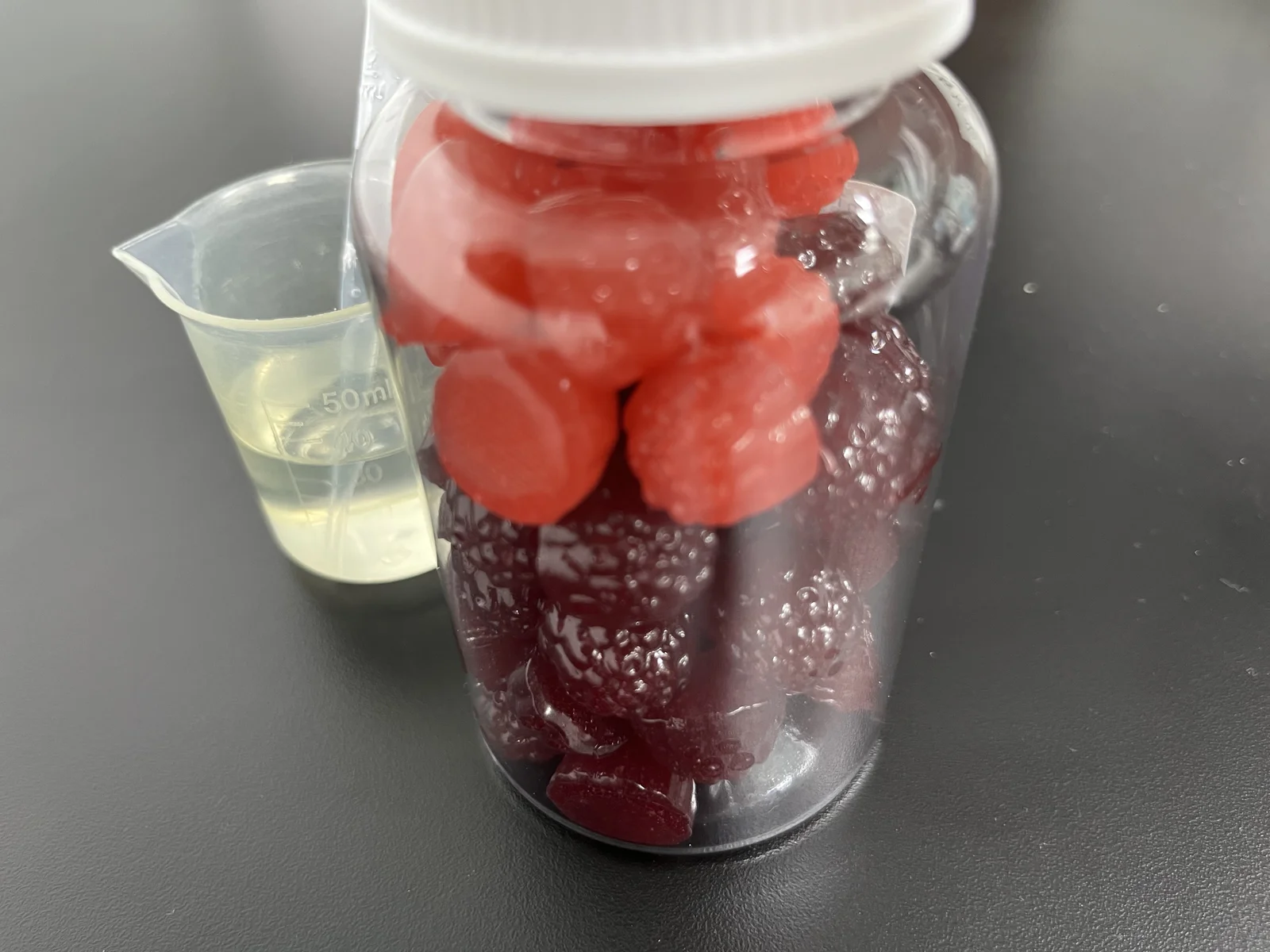 Red and purple gummy samples in a jar beside a beaker, illustrating probiotic strain suitability for gummies, including heat and acid tolerance, CFU specifications and shelf-life viability.