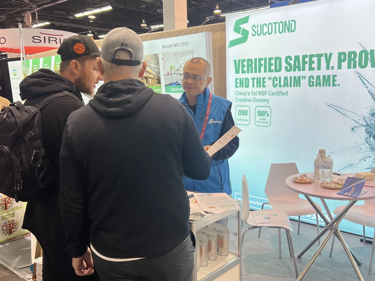 A SUCOTOND representative speaks with visitors beside the gummy display