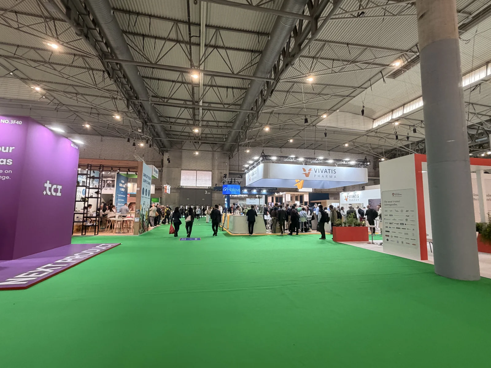 Visitors walk along a green-carpeted aisle inside the Vitafoods Europe exhibition hall
