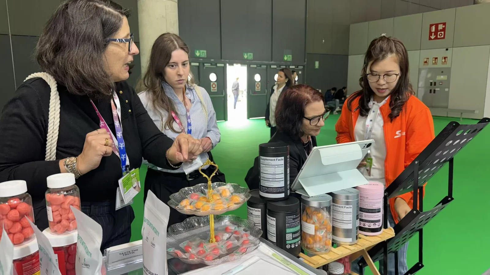 Visitors examine individually wrapped gummy samples with a SUCOTOND representative