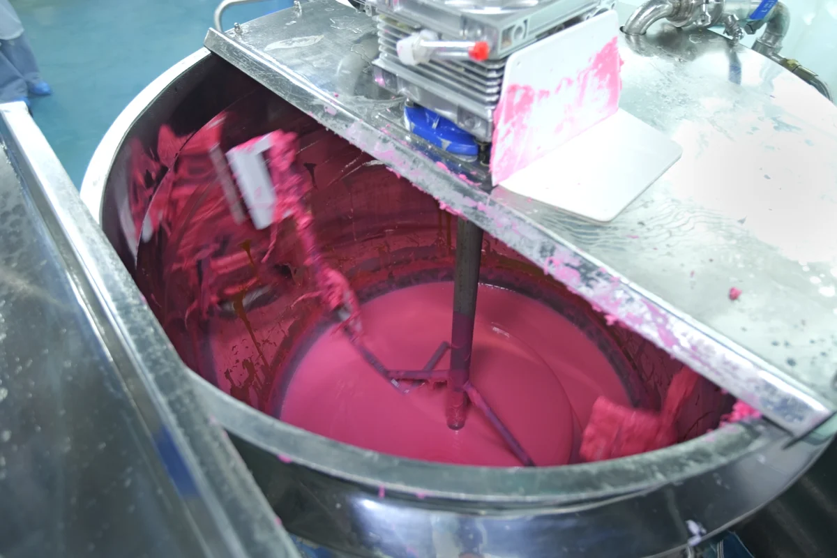 Pink gummy mass being mixed in a stainless steel tank