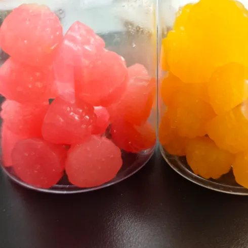 Pink and yellow gummy sample groups in separate clear containers for formulation comparison
