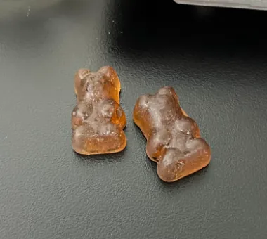 Two brown bear shaped gummy samples on a dark surface for a BCAA and creatine gummy concept