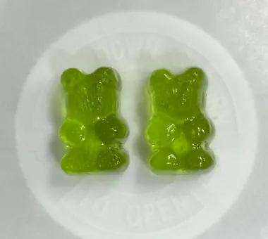 Two green bear shaped gummy samples displayed in a white dish for a vegan BCAA gummy concept