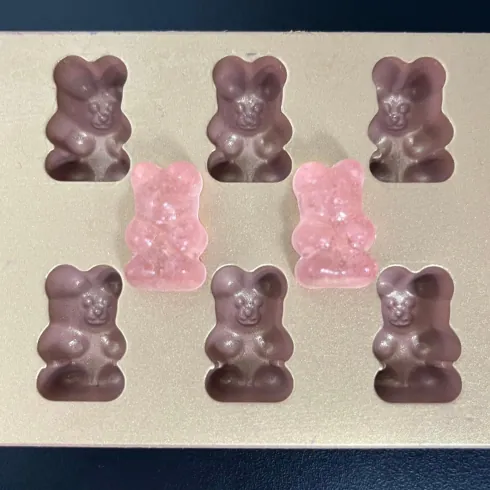 Dark purple gummy bears and two pale pink samples arranged for a beetroot powder and extract formulation comparison concept