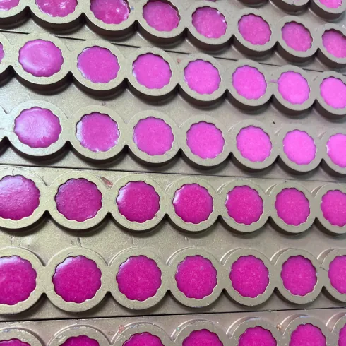 Magenta gummy mass deposited into rows of molds during a gummy production trial