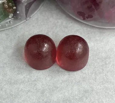Two dark red round gummy samples on a light surface for a Beetroot Extract Gummies concept