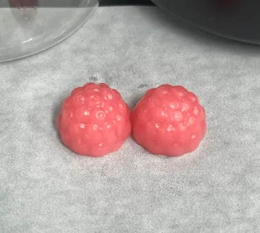 Two pink berry-shaped micronized creatine monohydrate gummies with vitamin D3 and K2, designed with finer creatine particles for a smoother taste and less powdery mouthfeel.