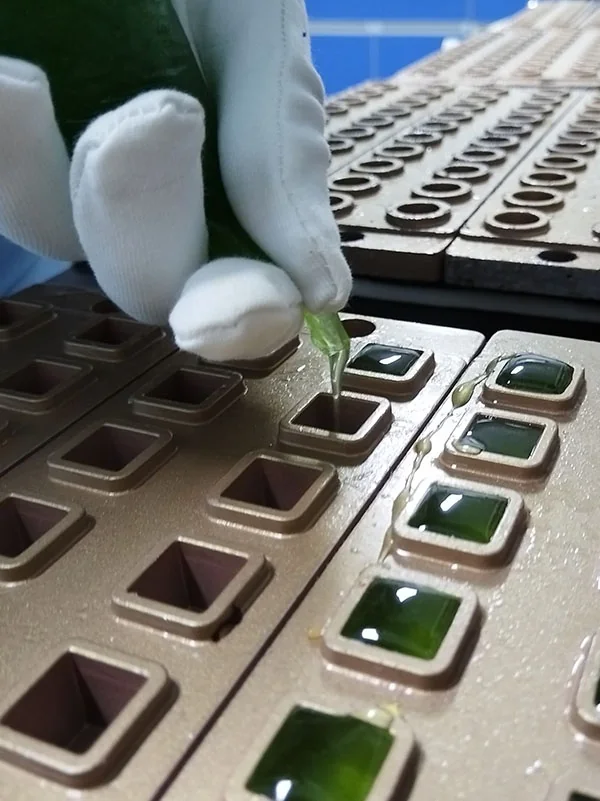 Pectin-based creatine gummy mixture being deposited into square molds during product development