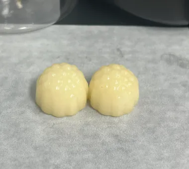 Two pale yellow Sugar-Free Women's Creatine Gummies developed by readjusting sweetness, texture and moisture and checking molding, taste and target-market nutrition requirements.