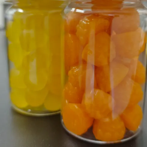 Yellow and orange gummy samples displayed in separate clear jars