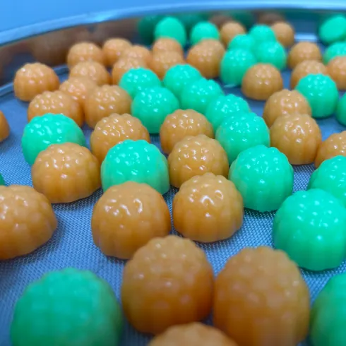 Green and amber gummy samples on a blue production surface