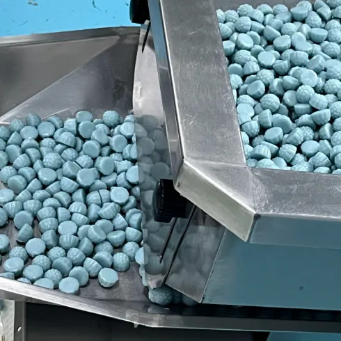 Blue gummy samples moving from a stainless steel processing hopper
