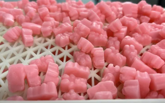 Pink gummy samples cooling on stacked production trays