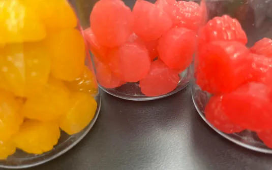 Red and yellow gummy samples in separate clear jars