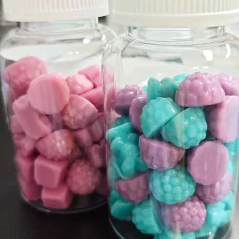 Pink and turquoise gummy samples displayed in two clear jars
