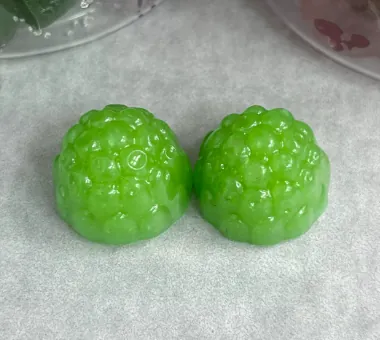 Two bright green berry-shaped gummy samples on parchment