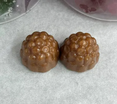 Two brown berry-shaped gummy samples on parchment