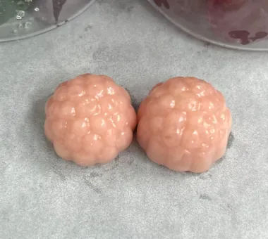Two soft pink berry-shaped gummy samples on parchment