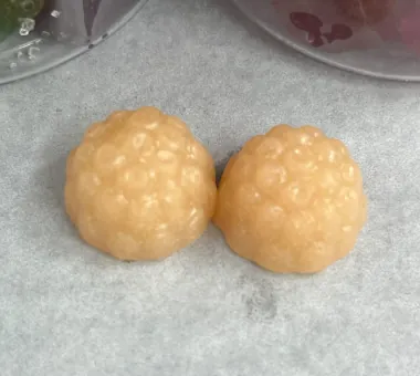 Two pale cream berry-shaped gummy samples on parchment
