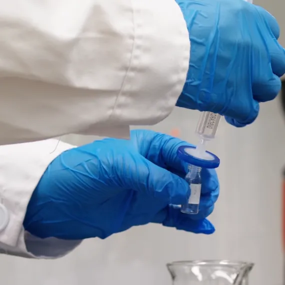 A laboratory technician filters a magnesium raw-material sample during quality checks for magnesium bisglycinate purity, chelation degree, pH and fine particle size used in high-content magnesium gummies.