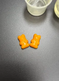 Two orange bear-shaped magnesium gummies for kids, representing a gentle magnesium glycinate formula concept with vitamin D3 and B6 for children's supplement brands.