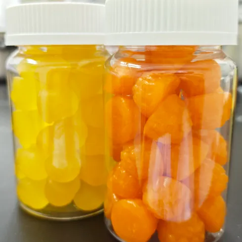 Bottled yellow and orange gummy samples representing pectin, gelatin and sugar-free base options for custom mushroom gummies and private label product development.