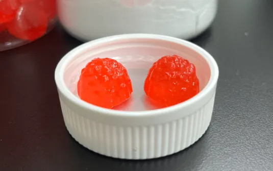 Two red gummy samples for a gut-health probiotic gummies project combining B. coagulans with encapsulated LGG, targeting 15 billion CFU per serving with accelerated stability testing.
