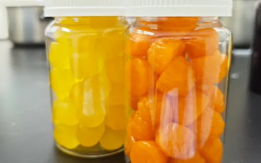 Yellow and orange gummy samples in clear bottles for a German citrus superfood gummy project