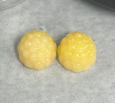 Two pale yellow berry gummies displayed individually for a whole turmeric root gummy concept