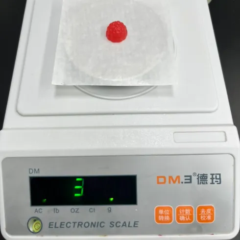 Red vitamin B12 gummy sample on a precision scale during finished-product quality control