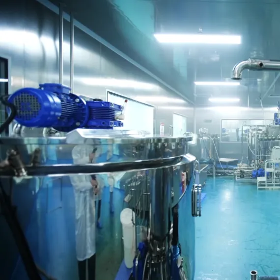 A stainless steel mixing tank in a clean vitamin gummy production room, used for staged multivitamin processing with low-temperature Vitamin C addition, separate B12 handling and high-shear emulsification for vitamins A and E.