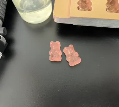 Two pale pink bear-shaped Vitamin B12 gummies representing light-protected production and batch-report support for micronutrient gummies with vitamin content that meets project requirements.