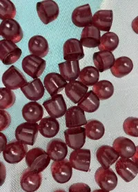 Dark red vitamin gummies in round and square shapes representing women’s formulas with vitamins A, C, D, E and B vitamins, including options combined with iron gummy projects.