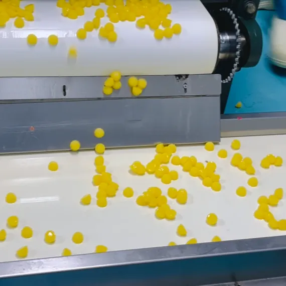 Yellow gummies moving through a production line for commercial women's creatine gummy manufacturing