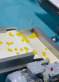 Yellow gummies moving through a conveyor during high-load women's creatine gummy production